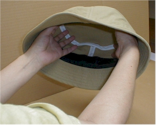 帽子内側に手をあてて押し広げる